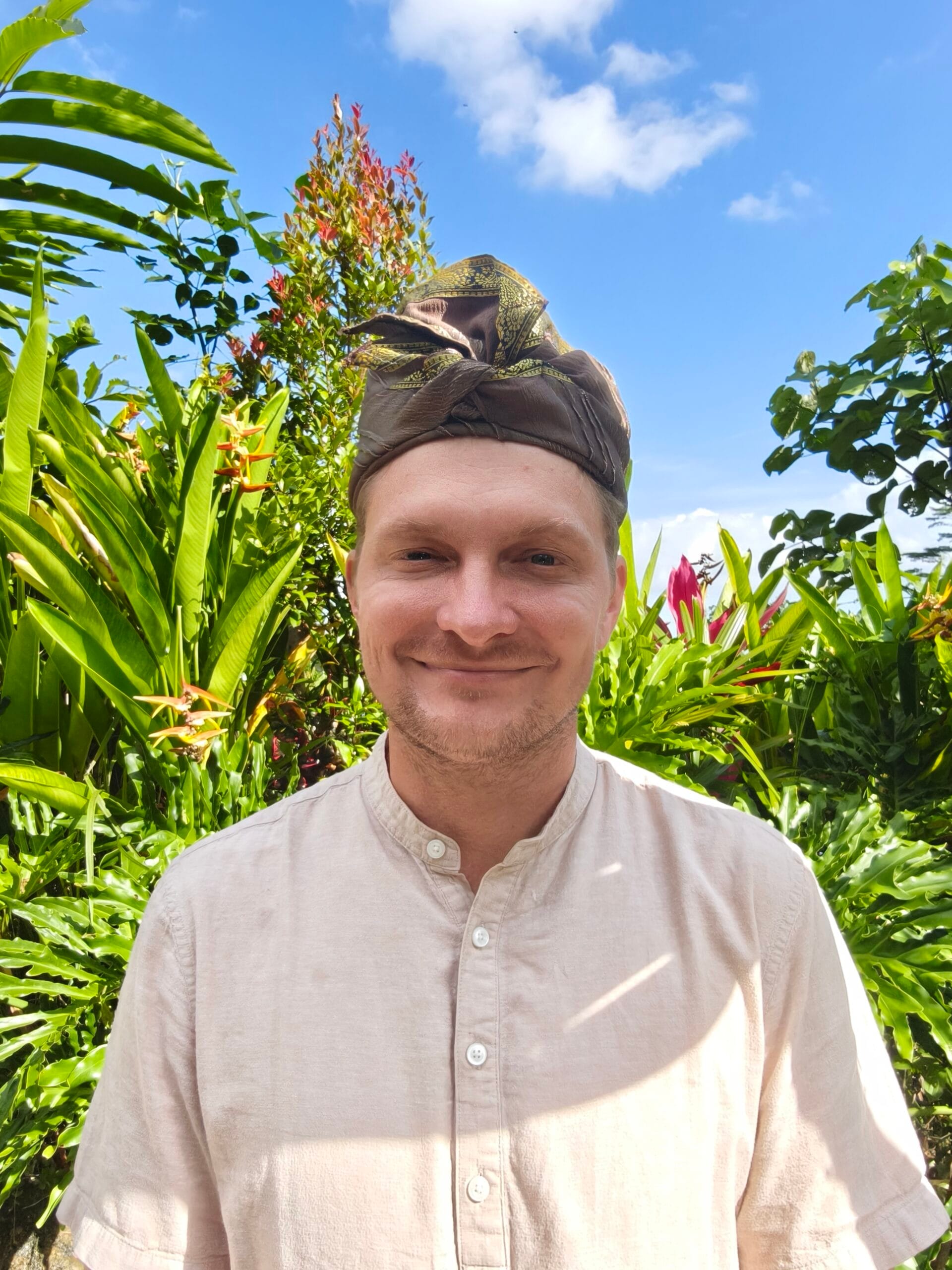 Eric Gonzalez-Payne outdoors, surrounded by tropical plants.