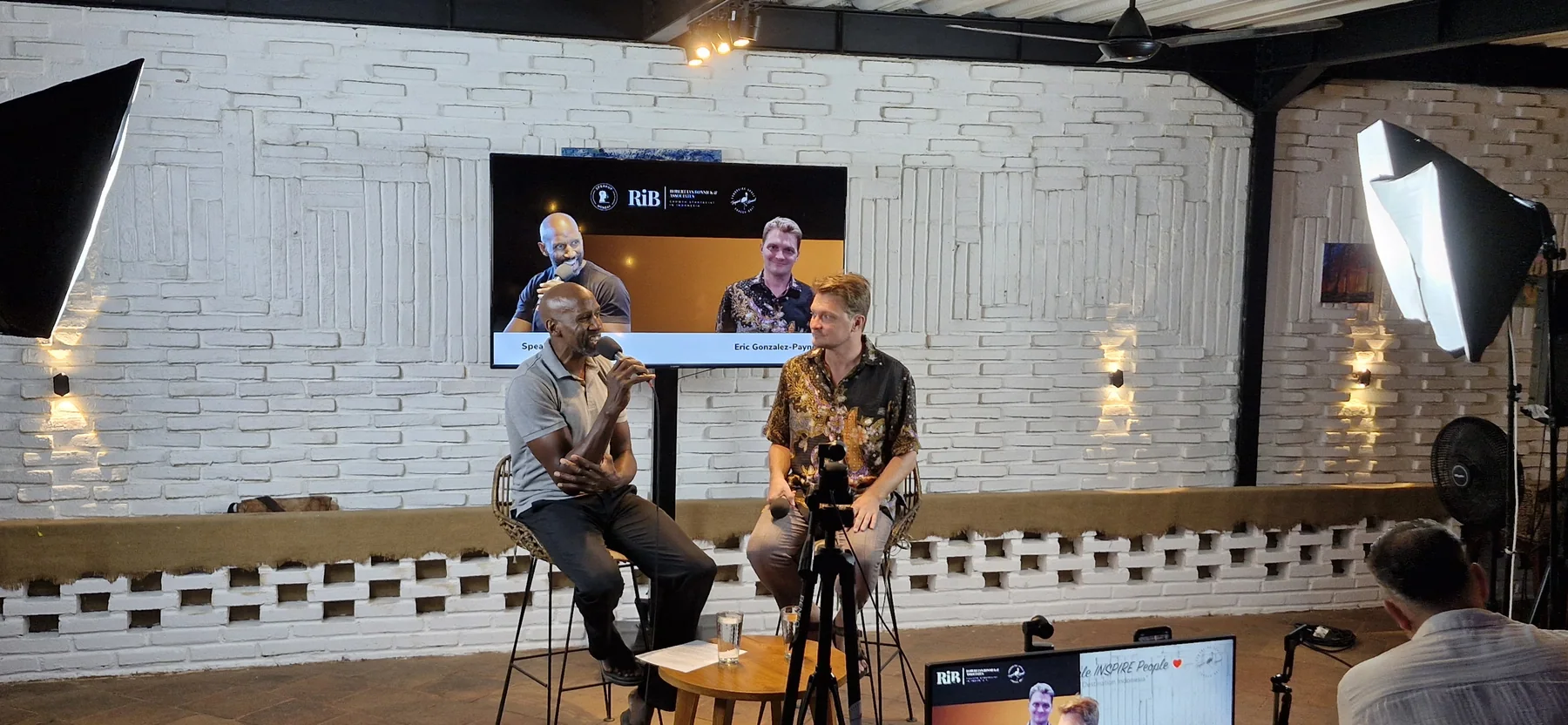 On stage at SpeakuP Monday in Bali, with microphones, an audience, and recording cameras.
